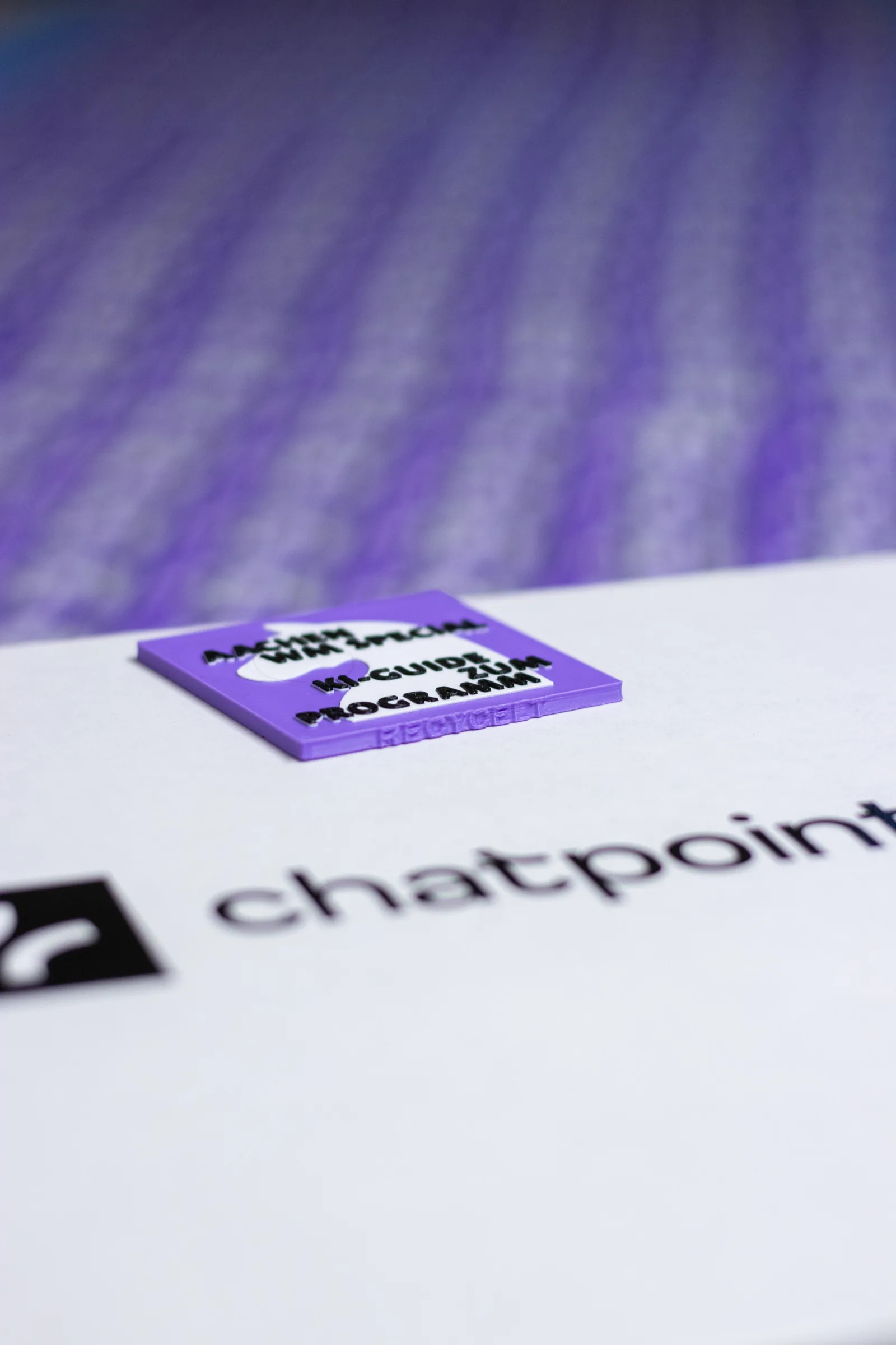 Ein violetter Programm-Chip vor einer unscharfen Reihe weiterer 3D-Drucke